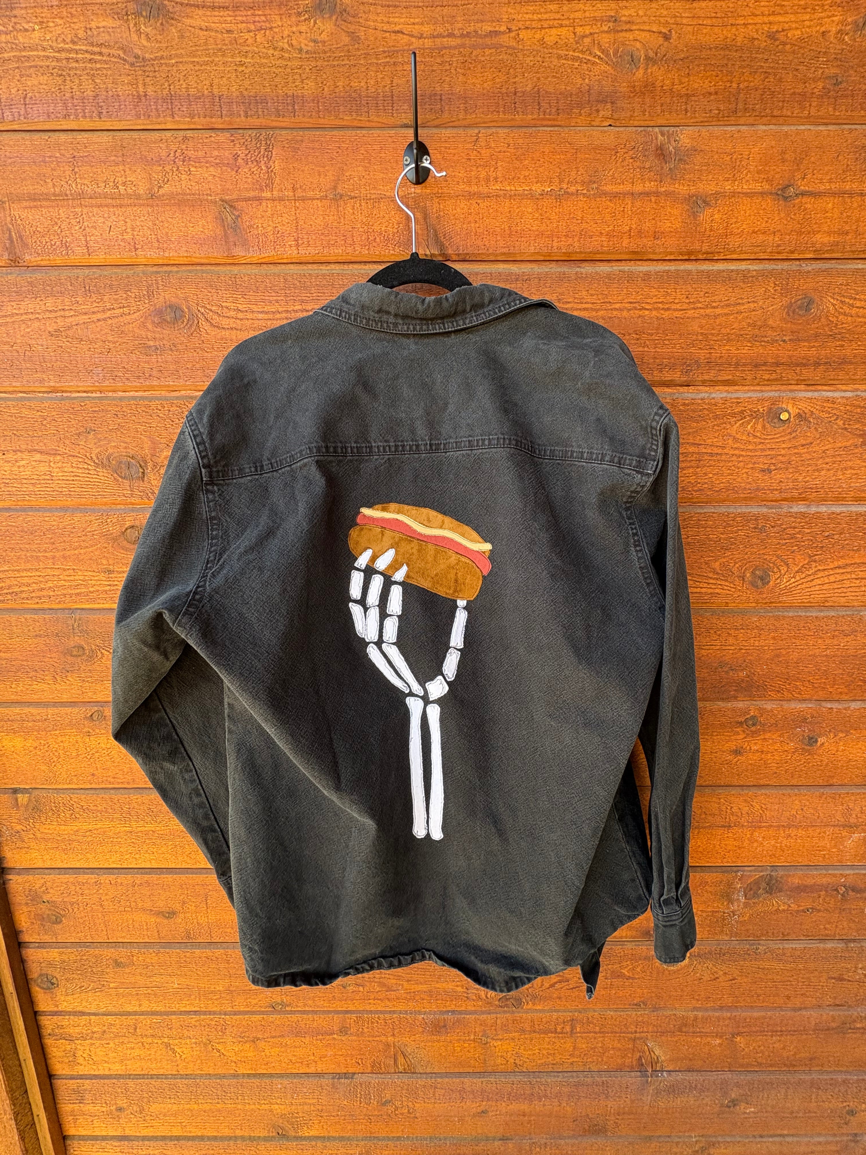 Black jacket with skeleton holding a hotdog.